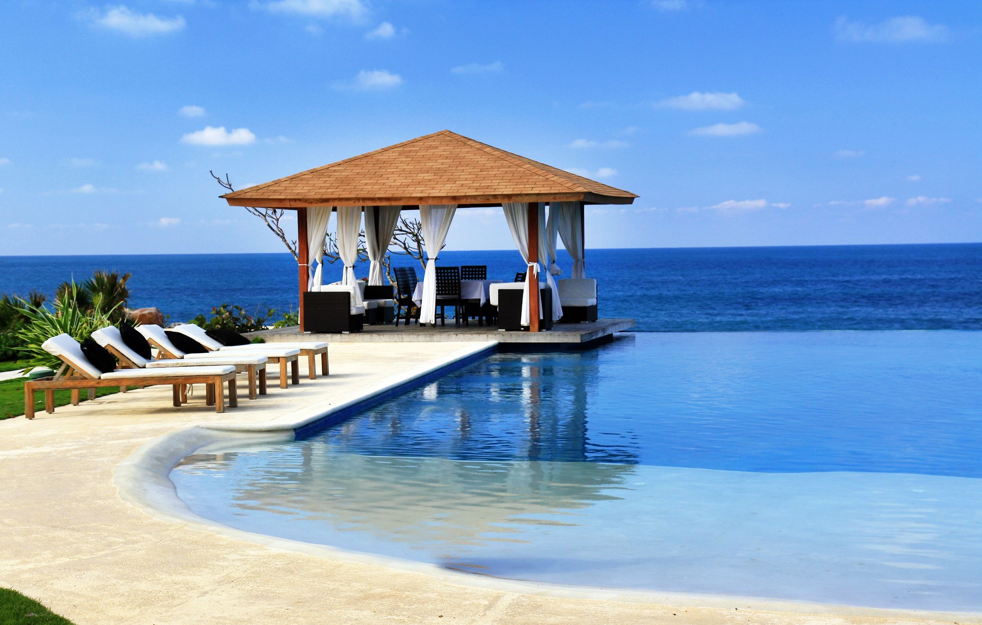 Pavilion and sun lounges next to a resort swimming pool